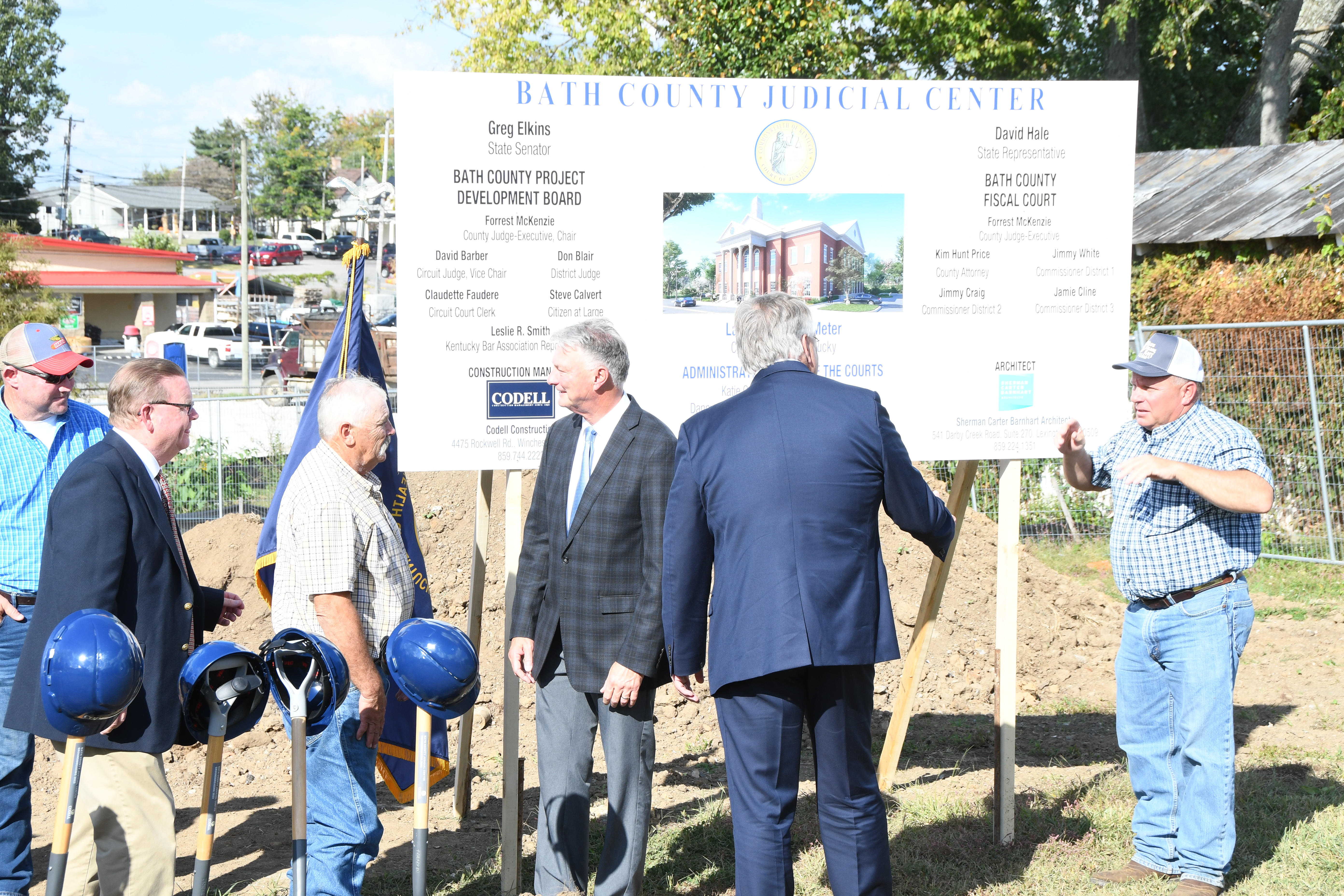 A small group standing and talking around a construction sign. 
