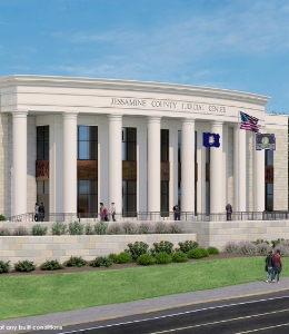 A beige brick building with large pillars in the front. Individuals walking around.
