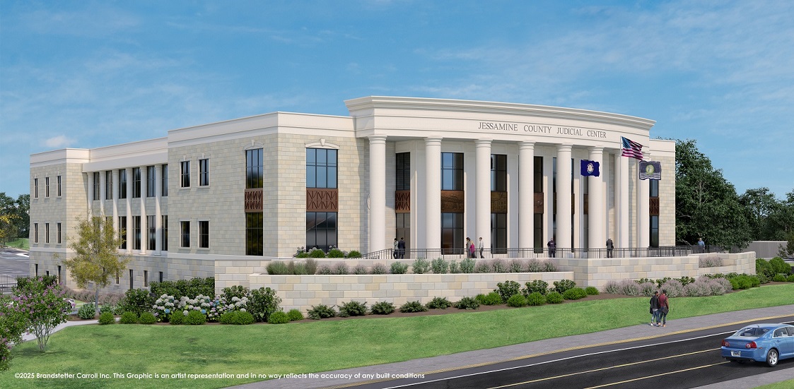 A beige brick building with large pillars in the front. Individuals walking around.