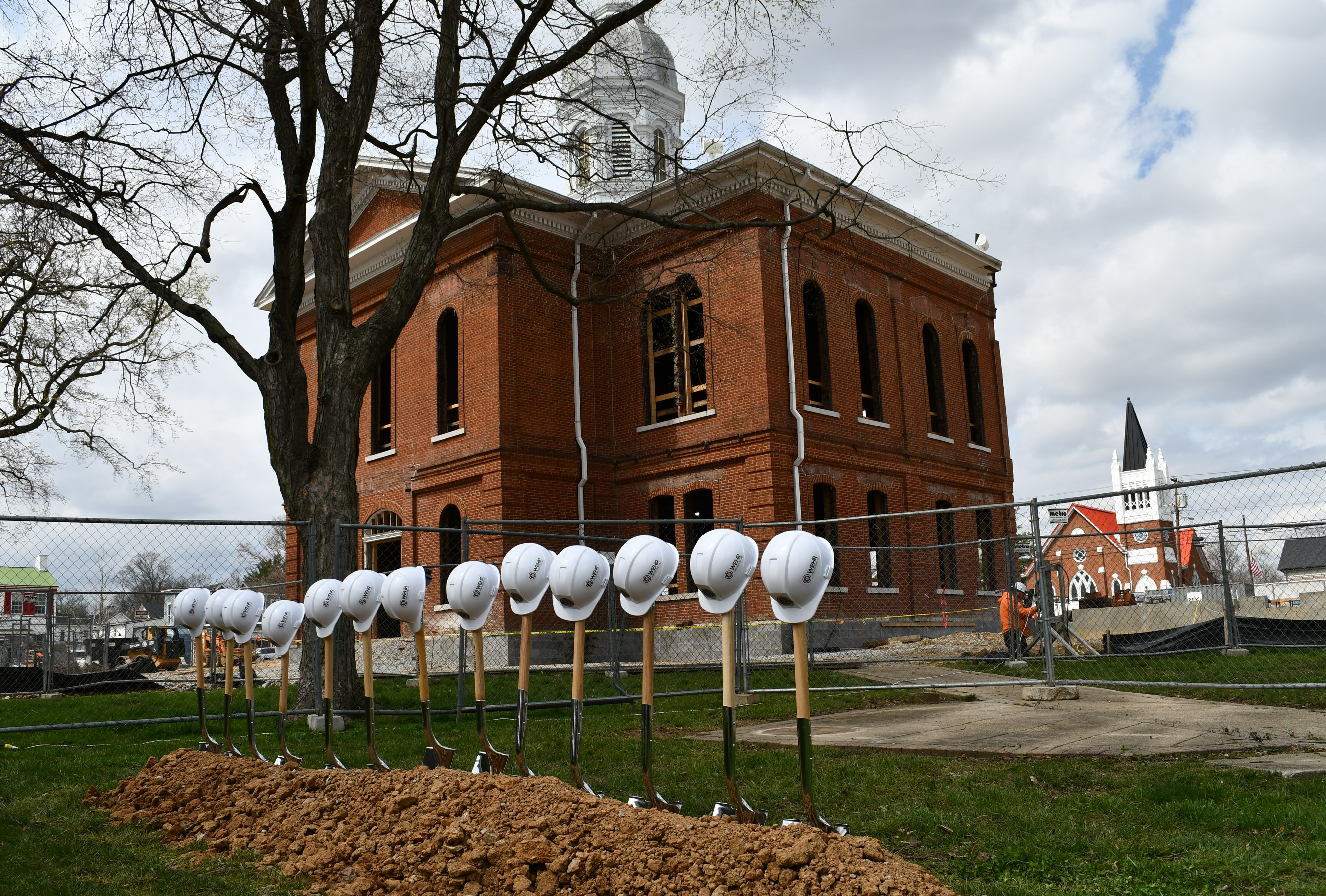 A red brick courthouse with shovels and hats lined in the front.