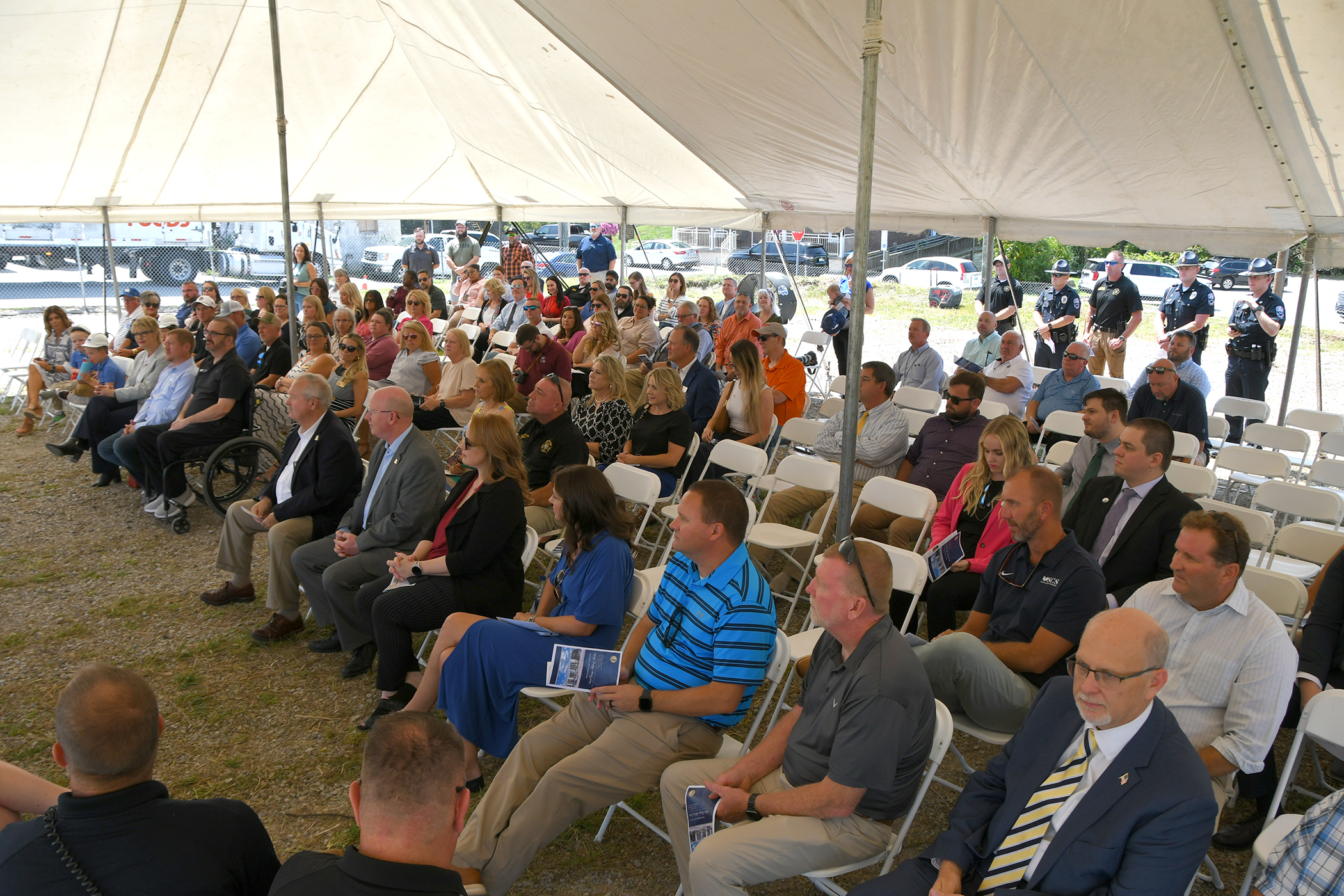 A white tent with a crowd sitting down for the ceremony. 