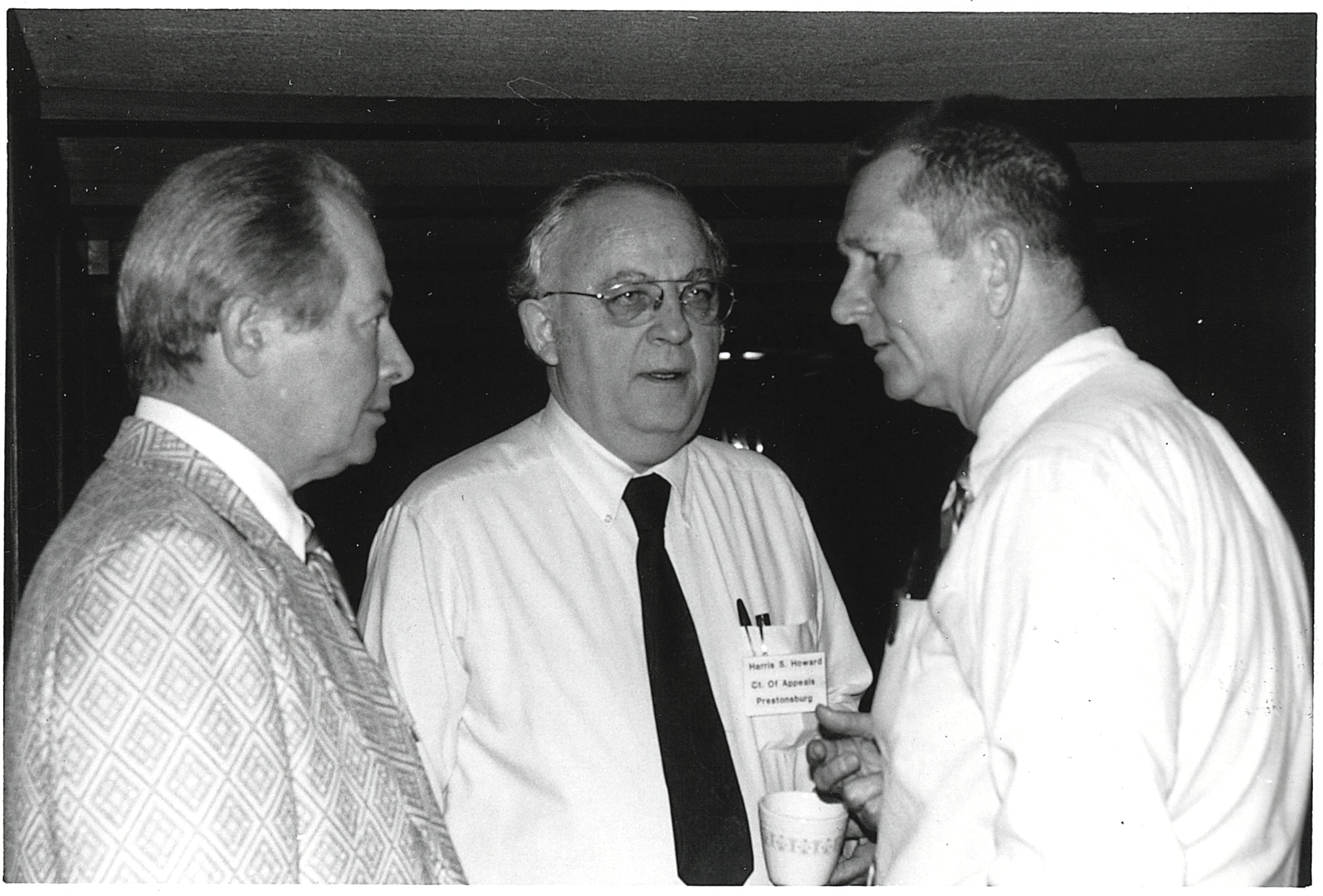 Judge Howard talking to others at a conference.